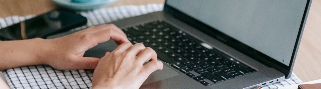 Kuvituskuva, läppärillä kirjoittavat kädet